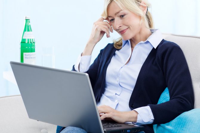 Frau middle-age mit Laptop_Heilwasserflasche im Hintergrund_861