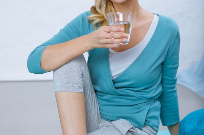 Trinken und Sport_Frau auf Yogamatte mit Heilwasserglas_4434