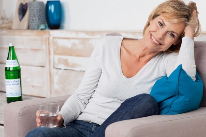 Frau middle-age mit Wasserglas im Sessel_1450